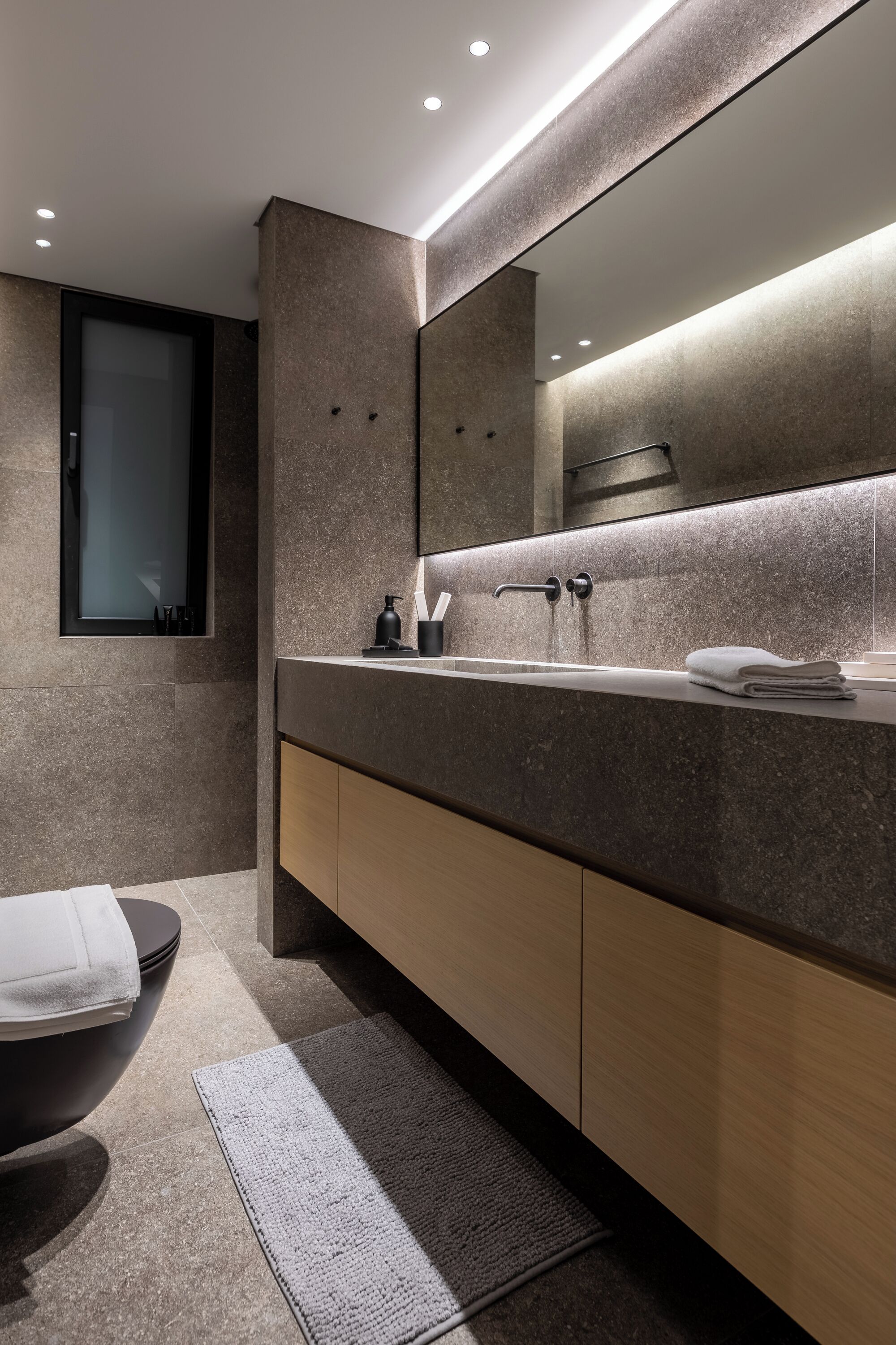 Un baño moderno con un espejo grande, un lavabo y un inodoro.