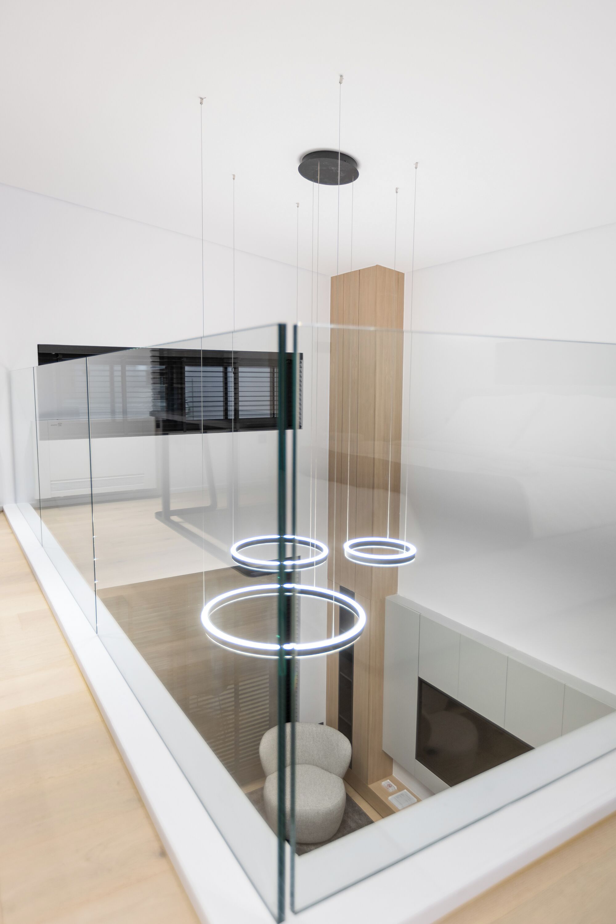 Un interior moderno con un separador de vidrio, un armario de madera y una lámpara de techo circular.