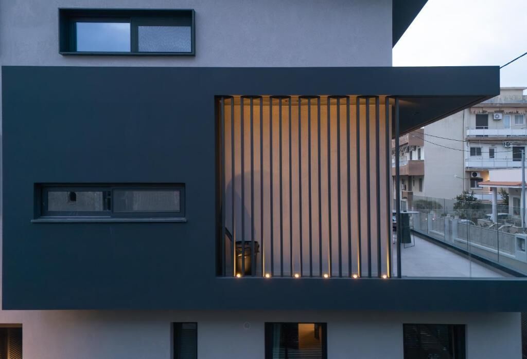 A modern building with a balcony, large windows, and a vertical light feature.