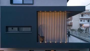 A modern building with a balcony, large windows, and a vertical light feature.