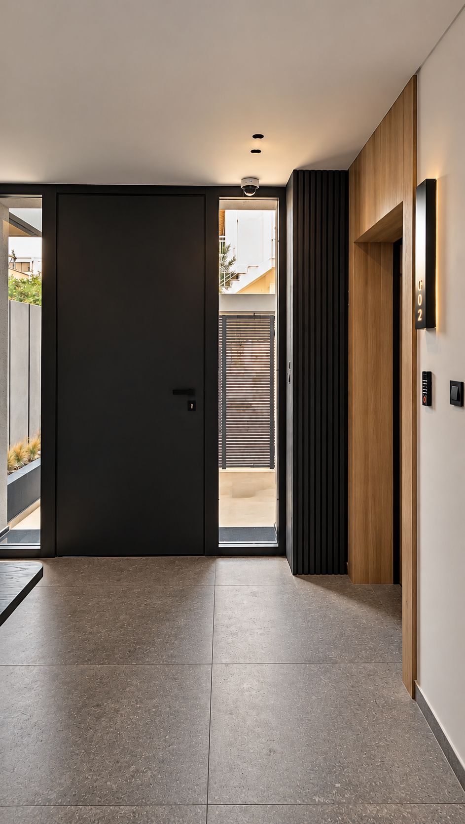 Un intérieur moderne avec une porte sombre, un mur recouvert de panneaux de bois et un sol carrelé.