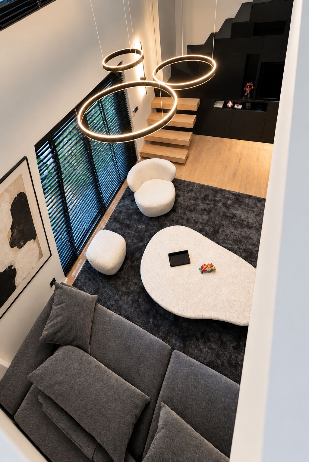 Um interior moderno com sofá, pufes, um tablet e um lustre.