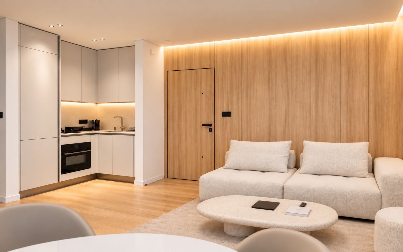 A modern living room with a sofa, a coffee table, and a kitchen area with cabinets and appliances.