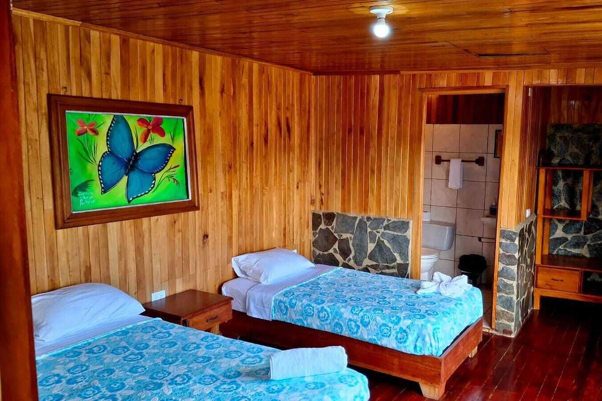 A wooden room with two beds, a stone wall, and a painting.