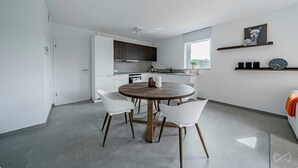 Une cuisine moderne avec des meubles blancs, une table de salle à manger ronde et une grande fenêtre.