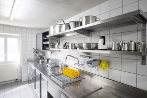Uma cozinha moderna com eletrodomésticos de aço inoxidável, paredes com azulejos brancos e diversos utensílios de cozinha nas prateleiras.