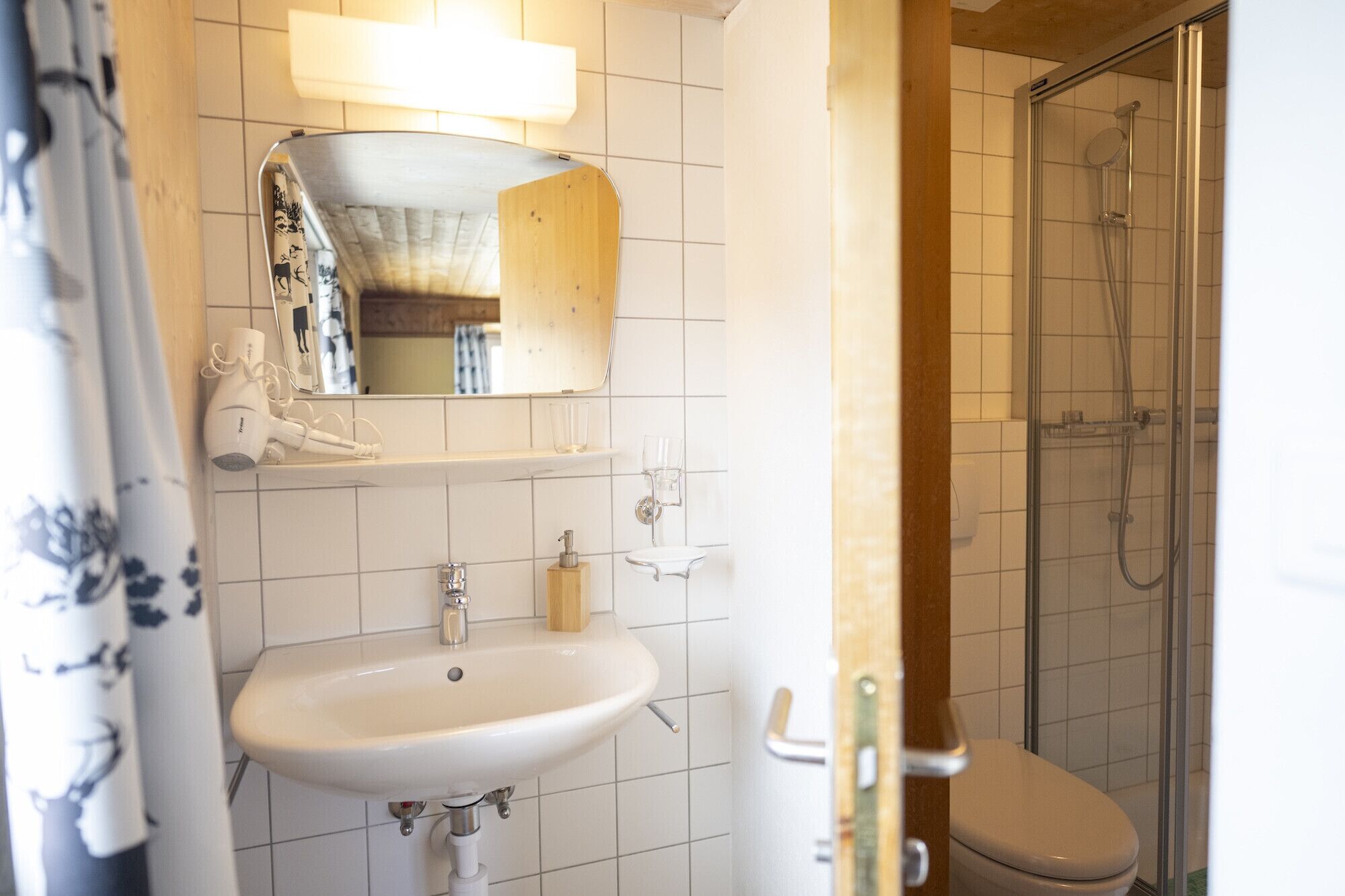 A bathroom with a white sink, a mirror, a towel, and a shower enclosure.