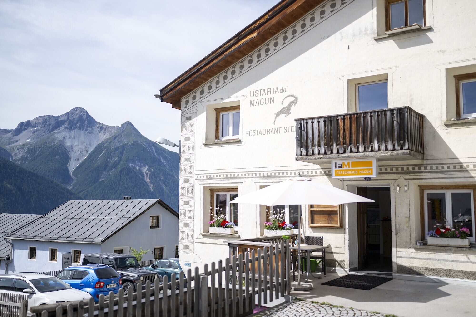 Ein Restaurant mit Blick auf die Berge, Außenbereich und eine Holzzahlung im Vordergrund.