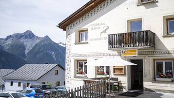 Ein Restaurant mit Blick auf die Berge, Außenbereich und eine Holzzahlung im Vordergrund.