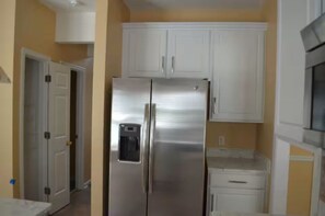 A kitchen with white cabinets, a stainless steel refrigerator, and a countertop.