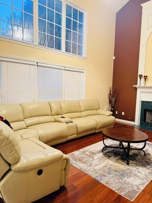 A living room with a beige sectional sofa, a round coffee table, and a fireplace.