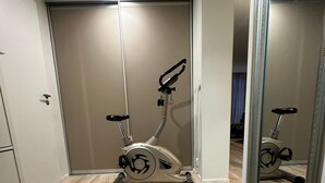 A room with a mirrored closet door, a standing exercise bike, and a wooden floor. - Business/couples - Parking - Wifi - Sleeps 3 (Jarfalla)
