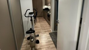 A hallway with an exercise bike, a kitchen area, and a door leading to another room. - Business/couples - Parking - Wifi - Sleeps 3 (Jarfalla)