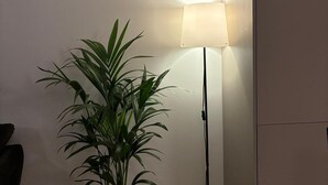A potted plant next to a floor lamp in a room with a plain wall. - Business/couples - Parking - Wifi - Sleeps 3 (Jarfalla)