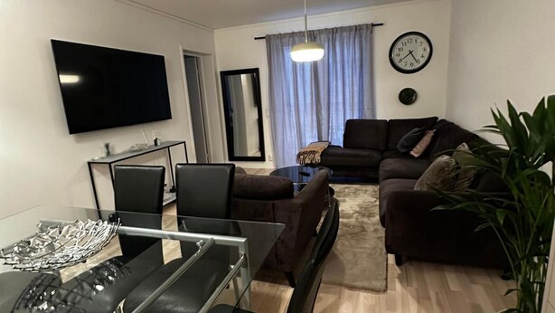 A living room with a flat-screen TV, a sofa, a coffee table, and a dining area with chairs. - Business/couples - Parking - Wifi - Sleeps 3 (Jarfalla)