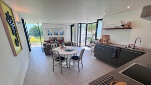 A modern kitchen with a dining area, large windows, and a view of the outdoors. - The Seahorse Torbay - Seaside hideaway for two with hot tub and movie room (Torquay)