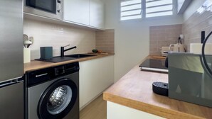Una cucina compatta con lavatrice, forno a microonde e lavello.