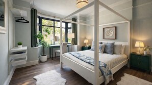 Un dormitorio con cama con dosel, un escritorio con silla, una lámpara colgante y vistas a la vegetación exterior.