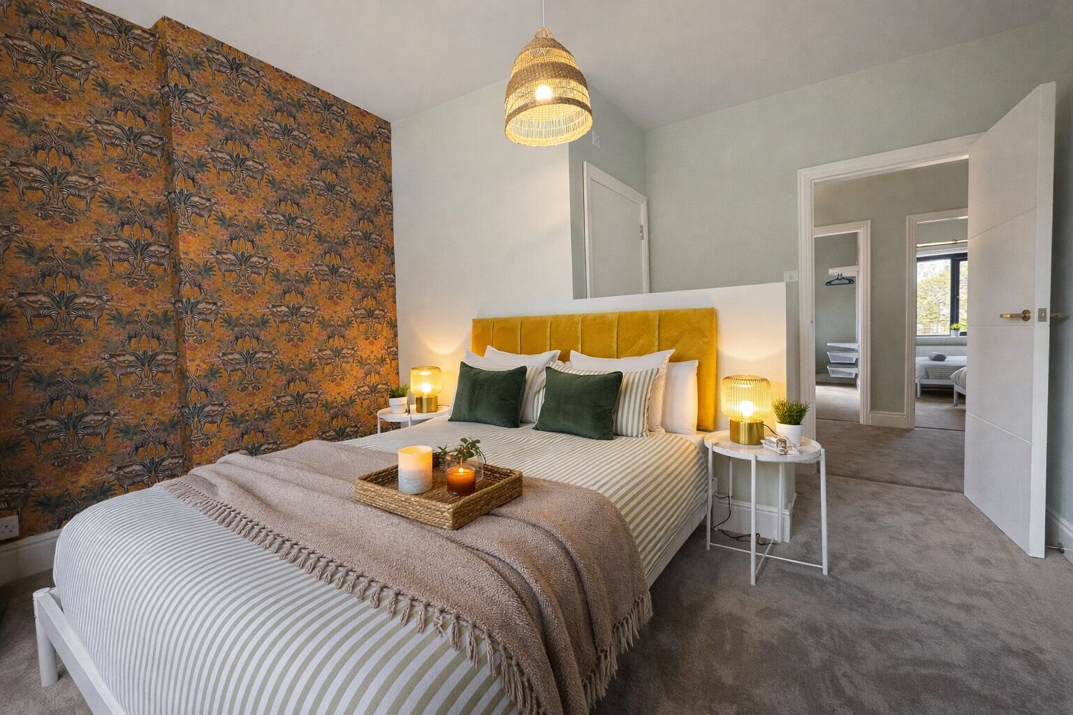 A bedroom with a bed, bedside tables, a hanging light fixture, and a patterned wall.