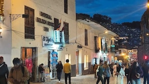 A cobblestone street with buildings, a sign for 'Golden Horses Inn,' and people walking. - Imperial Golden House Inn (Cusco)
