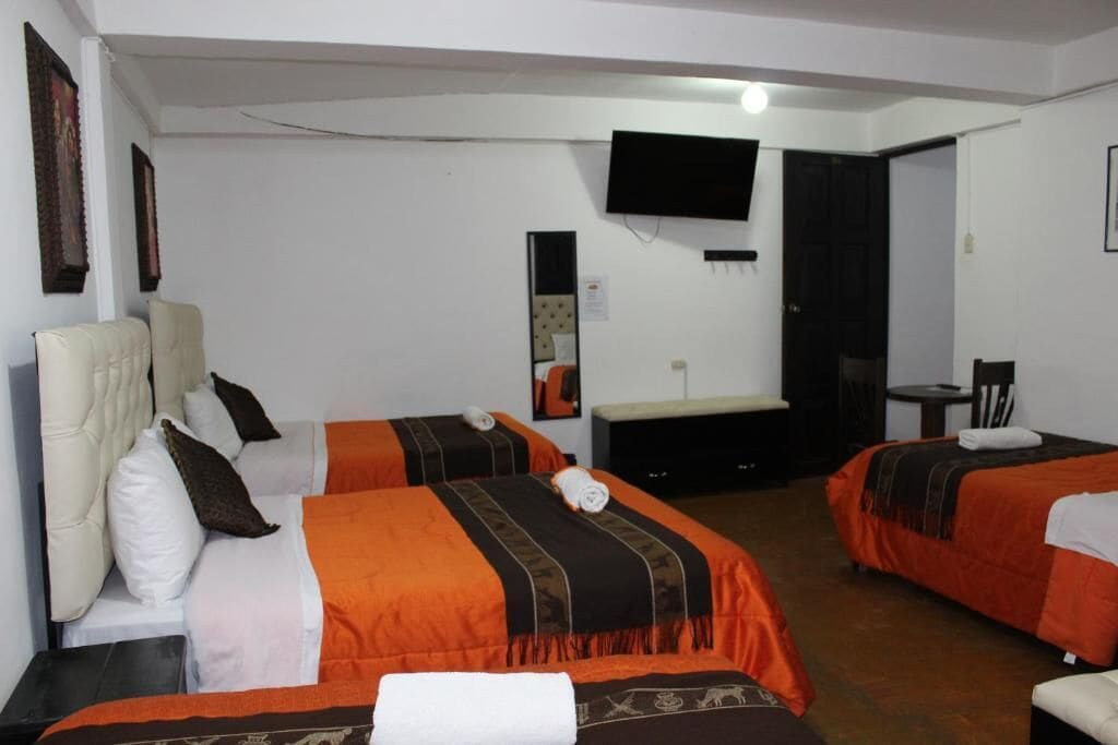 A hotel room with two beds, a TV, a desk, and a chair.