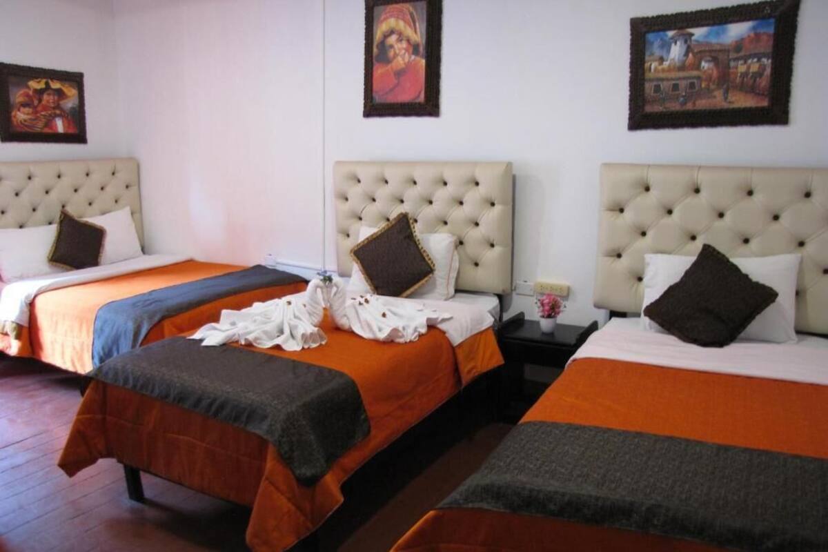 A hotel room with three beds, each with a tufted headboard, arranged in a row.