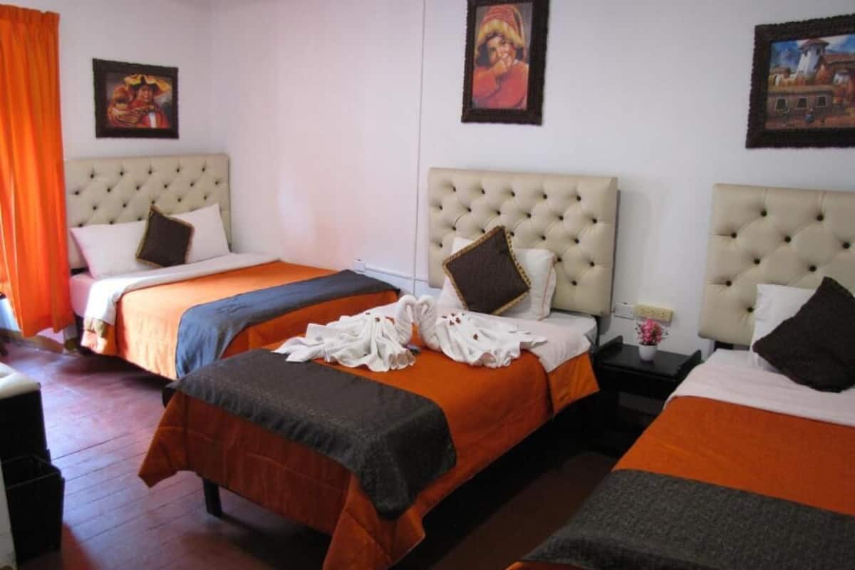 A hotel room with two beds, each with a headboard, a nightstand, and a wall-mounted picture.