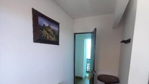 A hallway with a bench, a painting, a round table, and a door leading to another room. - Imperial Golden House Inn (Cusco)