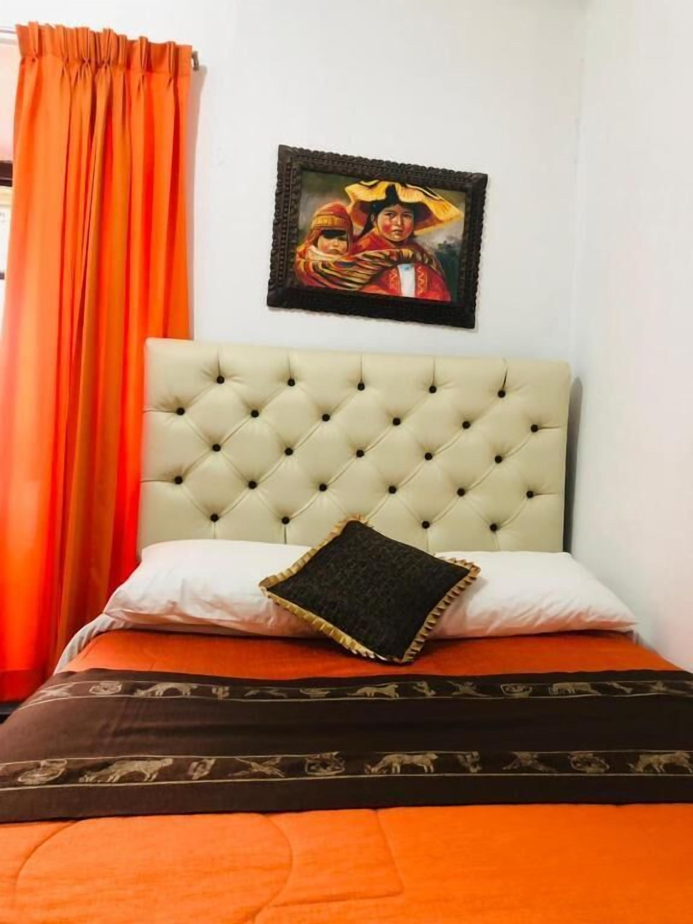 A bed with a tufted headboard, a single pillow, and a patterned bedspread.
