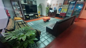 A living room with a sofa, a television, a coffee table, and a potted plant. - Imperial Golden House Inn (Cusco)