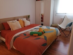 Ein Schlafzimmer mit Bett, Stuhl, Kleiderschrank und Fenster.