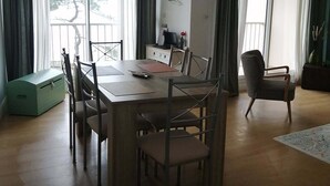 Un espace repas comprenant une table en bois, des chaises, un canapé et une vue sur l’extérieur.