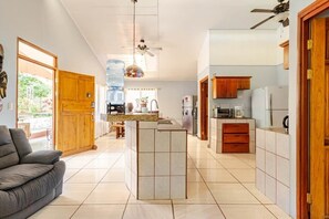 Eine geräumige Küche mit Kochinsel, Holzschränken und Deckenventilator.