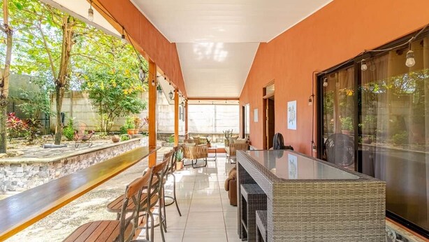 A covered outdoor seating area with a bar, chairs, and a view of greenery. - Casa Neju Diri - surf digital nomad hideaway (Nosara)