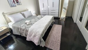 Ein Schlafzimmer mit Bett, Nachttischen, einem Kleiderschrank und einem Spiegel.