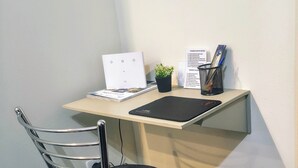 Ein Arbeitsplatz in der Ecke mit Schreibtisch, Stuhl, Laptop, Topfpflanze und Papierkorb.