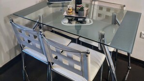 Ein moderner Essbereich mit einem Glastisch, Metallstühlen und dekorativen Wandregalen.