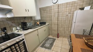 Eine Küche mit Herd, Spüle und Kühlschrank, einer Wanduhr und einem Teppich mit Muster.