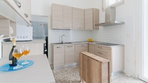 Ett modernt kök med ljusa träskåp, en diskho i rostfritt stål och en mikrovågsugn.