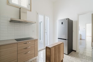 Eine Küche mit Edelstahl-Dunstabzugshaube, Kühlschrank, Holzschränken und einer Arbeitsplatte.