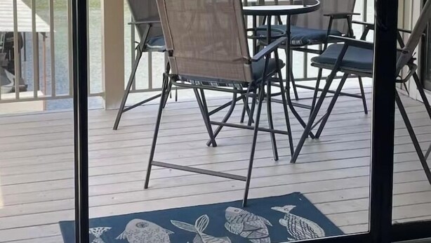 A balcony with a view of a lake, metal chairs, a small table, and a decorative rug. - Location Location! Cute cozy condo! Close to everything! (Osage Beach)