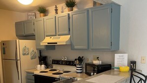 A kitchen with light blue cabinets, a stainless steel refrigerator, a stove, and two bar stools. - Location Location! Cute cozy condo! Close to everything! (Osage Beach)