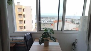 A small kitchen with a window, a potted plant, a table, and a chair. - Magnifique Studio Au Petit Nid Douillet Face Mer est Port (Narbonne)