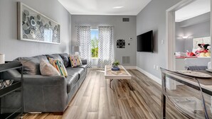 Un salon moderne avec un canapé gris, une table basse et un téléviseur fixé au mur.