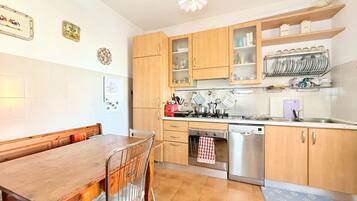 A kitchen with wooden cabinets, a dining table, and a dishwasher.