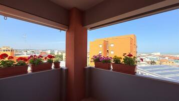 A balcony with potted plants and a view of buildings.