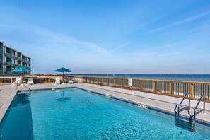 A swimming pool with a wooden deck, lounge chairs, and a view of the ocean. - 🏝️Sound-Front | Two Balconies | Steps to the Beach | Palm Beach Club #206🏝️ (Pensacola Beach)