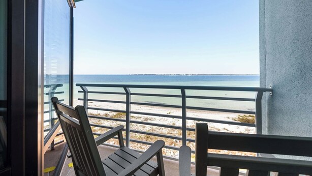 A balcony with a view of the sea, a chair, and a table. - 🏝️Sound-Front | Two Balconies | Steps to the Beach | Palm Beach Club #206🏝️ (Pensacola Beach)