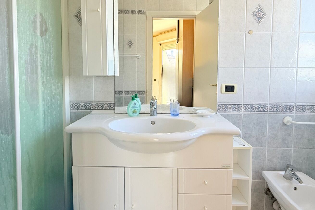 A bathroom with a white sink, a mirror, and a towel rack.