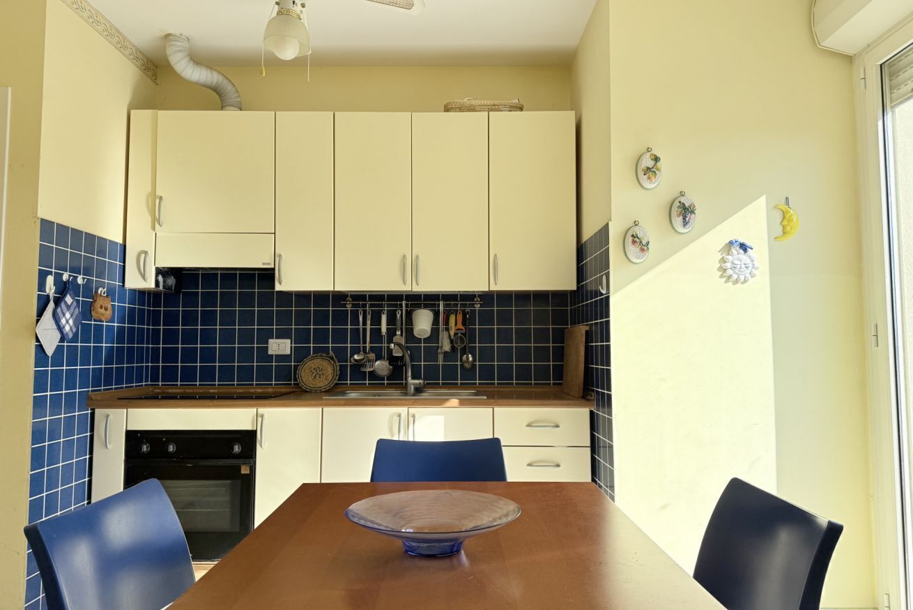 A kitchen with white cabinets, a blue tiled backsplash, and a wooden dining table with chairs.